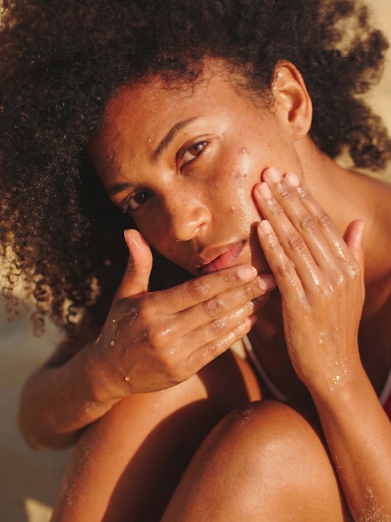 Woman applying natural skincare with coconut oil for acne-prone skin.